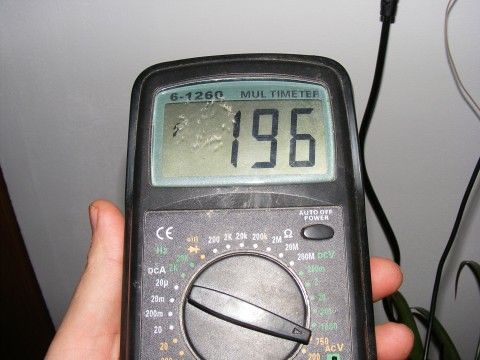 Цифровой мультиметр в руках мастера замеряет напряжение в розетке
