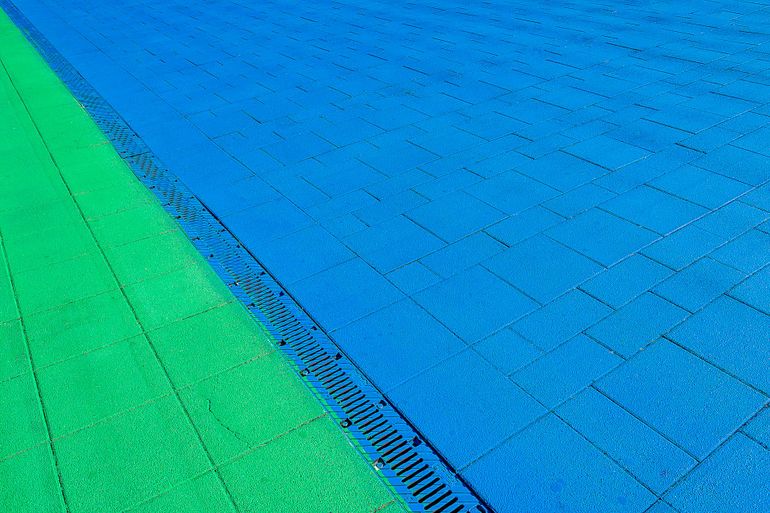 Линейный водоотводный лоток с решёткой в мощёной дорожке у площадки