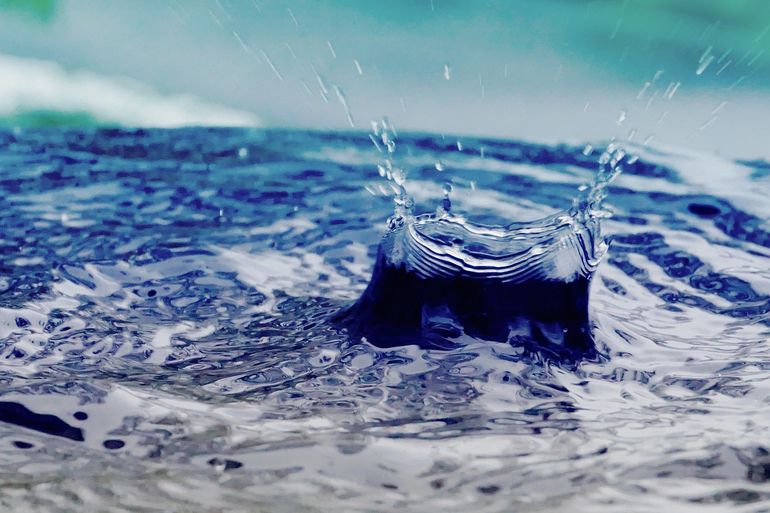Дождевая бочка с каплями воды у стены для сбора стока с крыши