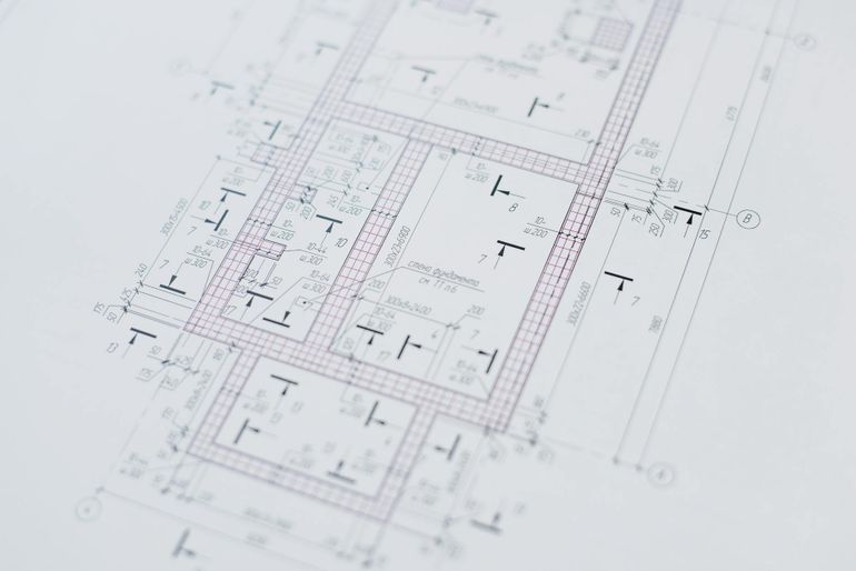 Крупный план архитектурного чертежа с разметкой помещений и размеров на бумаге