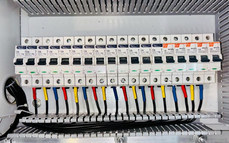 Распределительный щит с рядом автоматов и аккуратно разведёнными цветными проводами