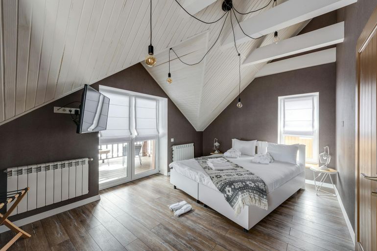 Мансардная спальня со скошенным потолком и расстановкой мебели под скатами