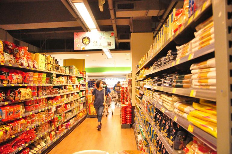Широкий проход между полками с продуктами, два человека свободно расходятся
