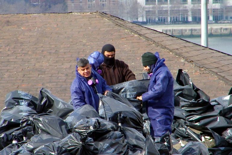 Рабочие монтируют утеплитель в каркасную конструкцию стены