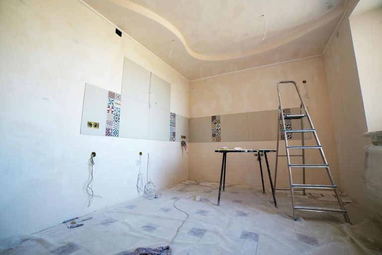 Комната на этапе чистовой отделки с краской, плиткой и малярными инструментами