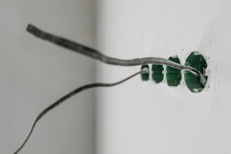 Подрозетник с торчащими проводами в неоштукатуренной стене на этапе черновой электрики