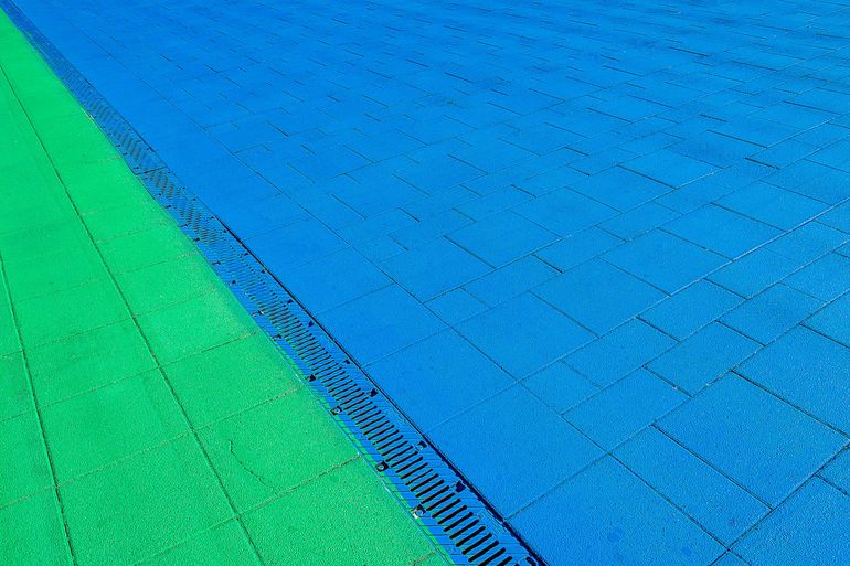 Линейный водоотводный лоток с решёткой в мощёной дорожке у площадки