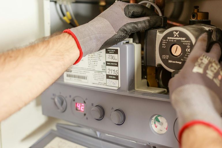 Руки специалиста настраивают газовый котёл с приборами в котельной частного дома