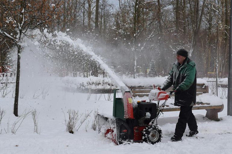 Мужчина чистит снег снегоуборщиком зимой — пример крупной сезонной техники для хранения