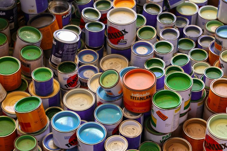 Ряд банок краски разных цветов на полке магазина