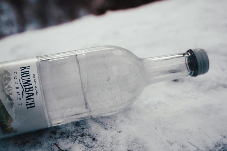 Замёрзшая пластиковая бутылка с водой лежит на снегу при минусовой температуре