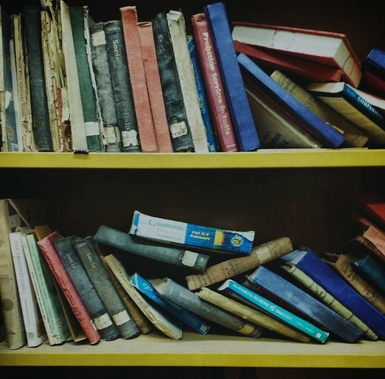 Плотно забитая книгами и вещами полка без свободного пространства между предметами