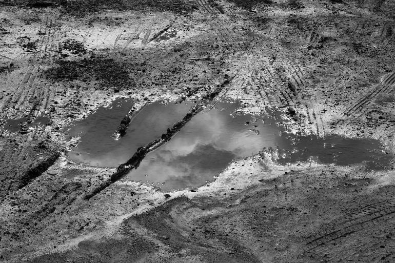Лужа застоявшейся воды на плотной грунтовой поверхности после дождя