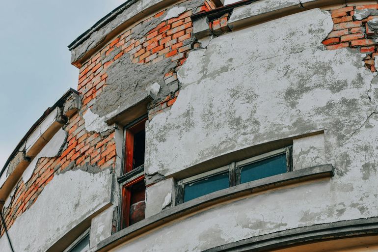 Трещины и разрушение на старой кирпичной стене без защитного штукатурного слоя