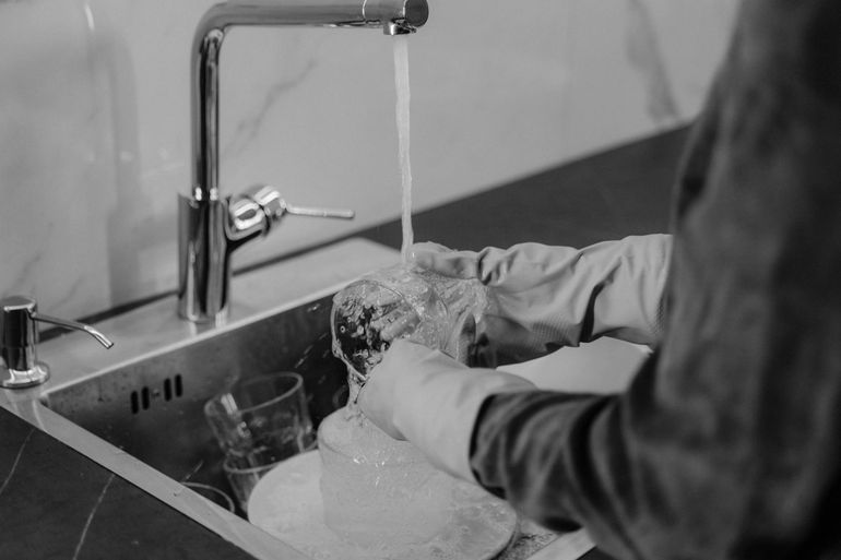 Струя воды льётся из кухонного крана в раковину