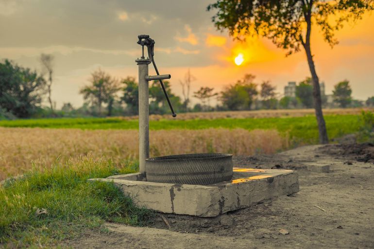 Старая водяная колонка в сельской местности на закате