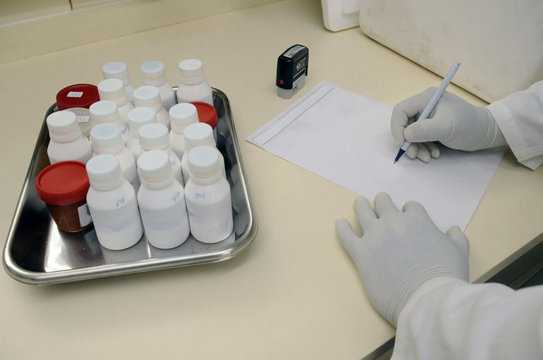 Лаборант записывает результаты анализа рядом с пробирками образцов