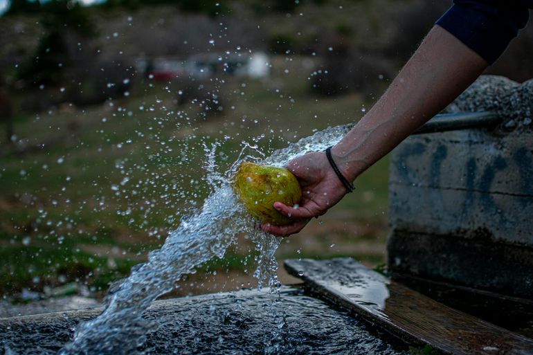 Струя воды из уличного крана при мытье фрукта