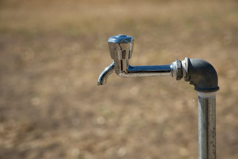 Металлический водопроводный кран крупным планом со струёй воды