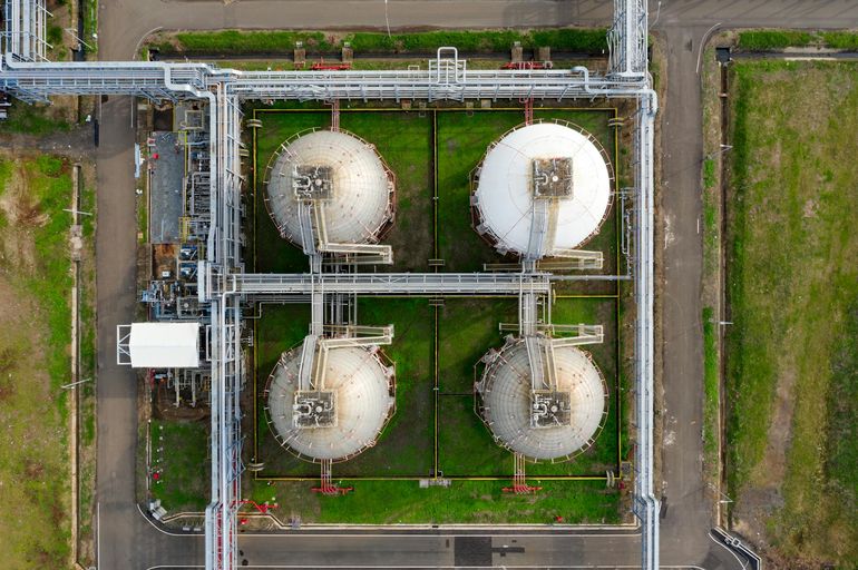 Крупные цилиндрические резервуары для хранения газа на промышленной площадке сверху