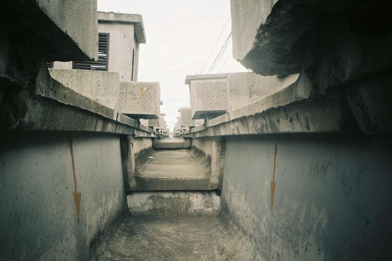Бетонный канализационный канал уходит к промышленным сооружениям вдоль склона