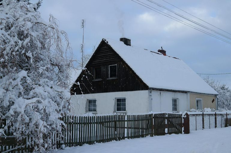 Заснеженный загородный дом среди зимнего леса перед консервацией на зиму