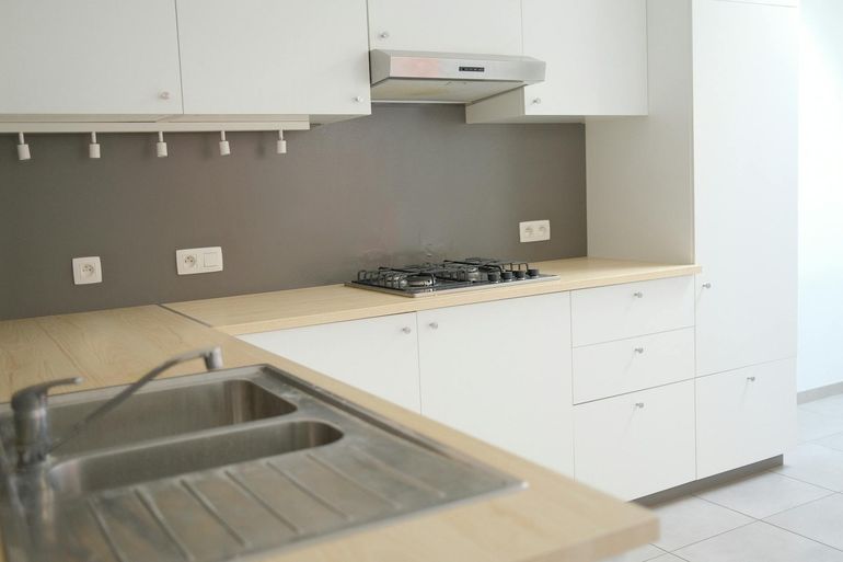 Минималистичная кухня с плитой и рабочей столешницей под бытовую технику