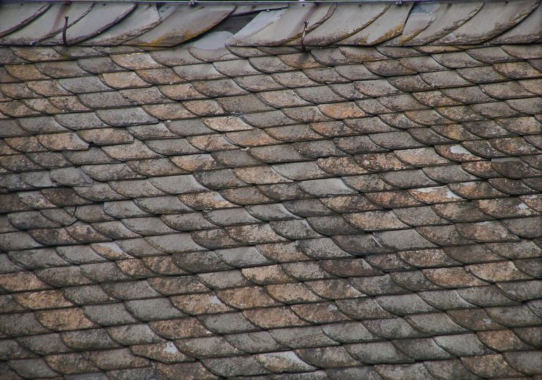 Старая крыша в процессе ремонта со снятым покрытием и видимой конструкцией скатов
