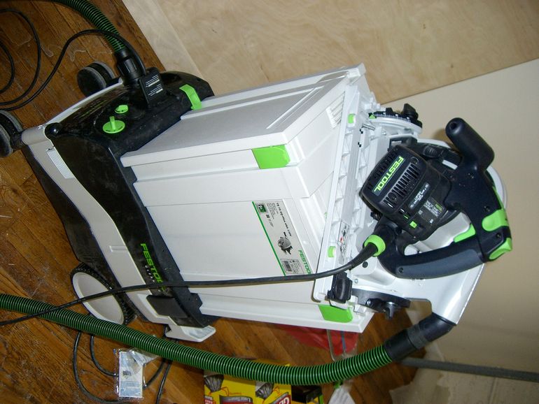 Пылесос-экстрактор Festool рядом с ручной пилой и кейсом для мастерской